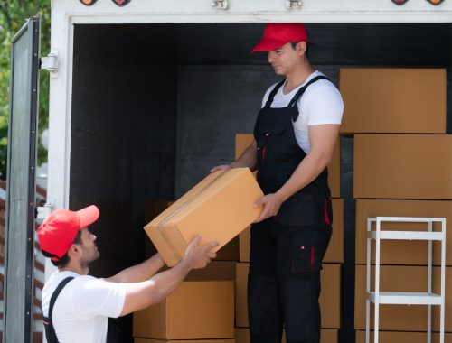 Asian delivery man in uniform delivering package to customer in back of truck.