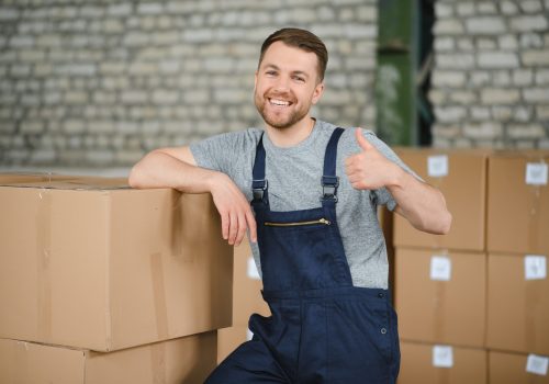 Warehouse worker carrying a carton for delivery to production stock